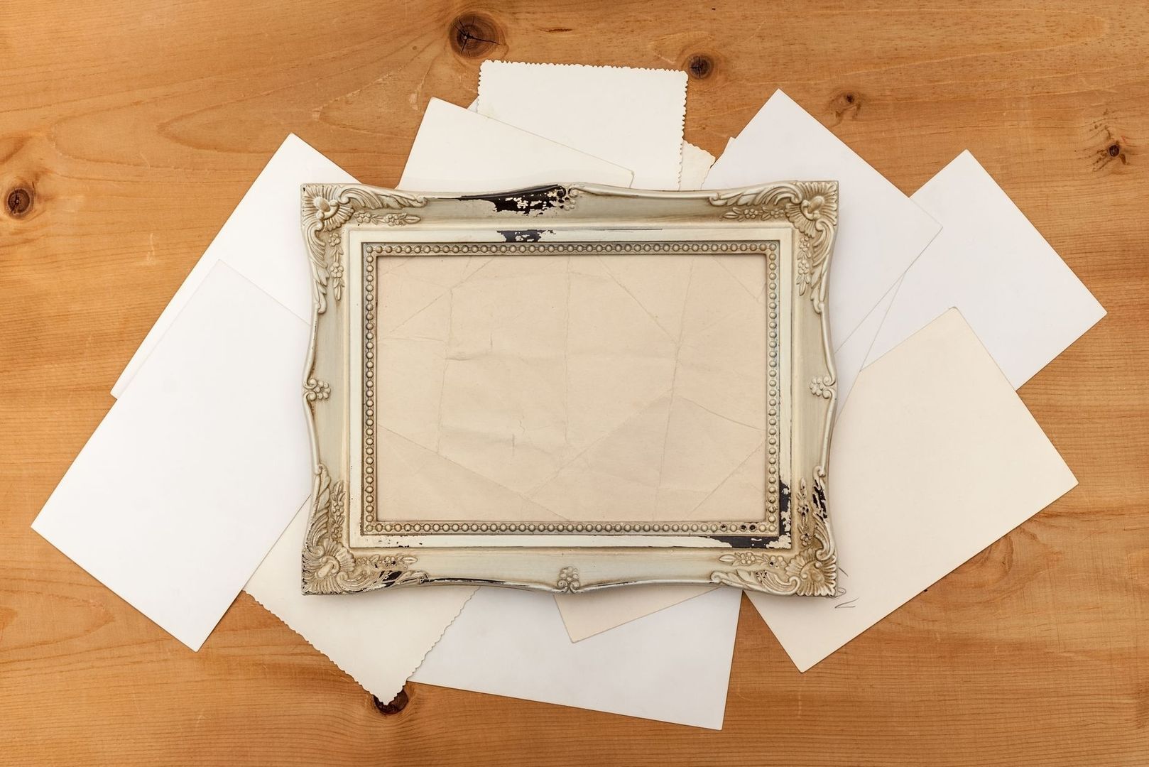 Verzierter leerer Bilderrahmen auf empfindlichen Papierbögen ausgebreitet