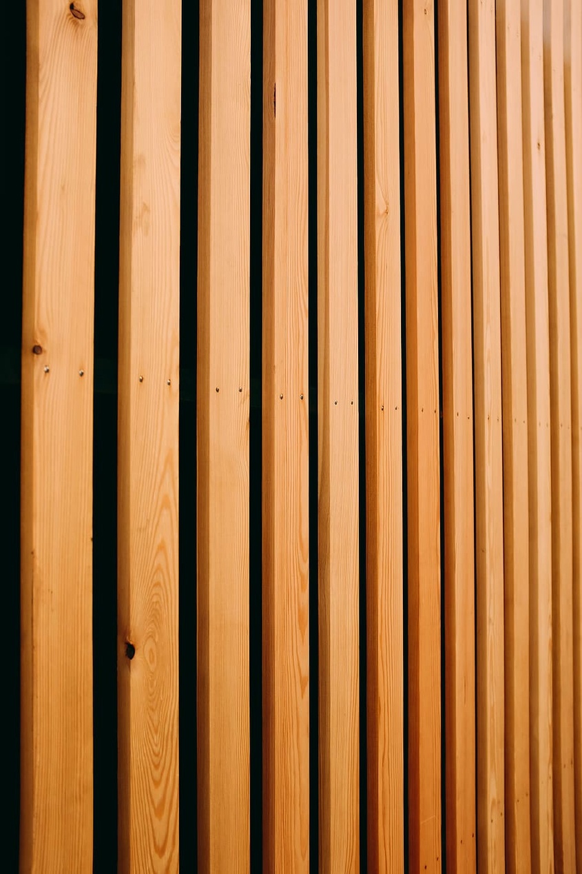 Nahaufnahme von Holzlamellen eines Akustikpaneels, die die Textur des Holzes und den dunklen Filz dazwischen zeigen.